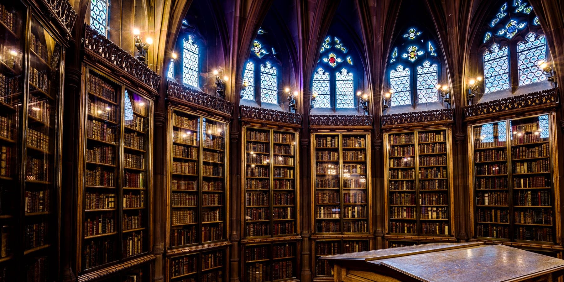 The book-lined reading room of the John Rylands Library in Manchester, its gothic cases filled with bound volumes