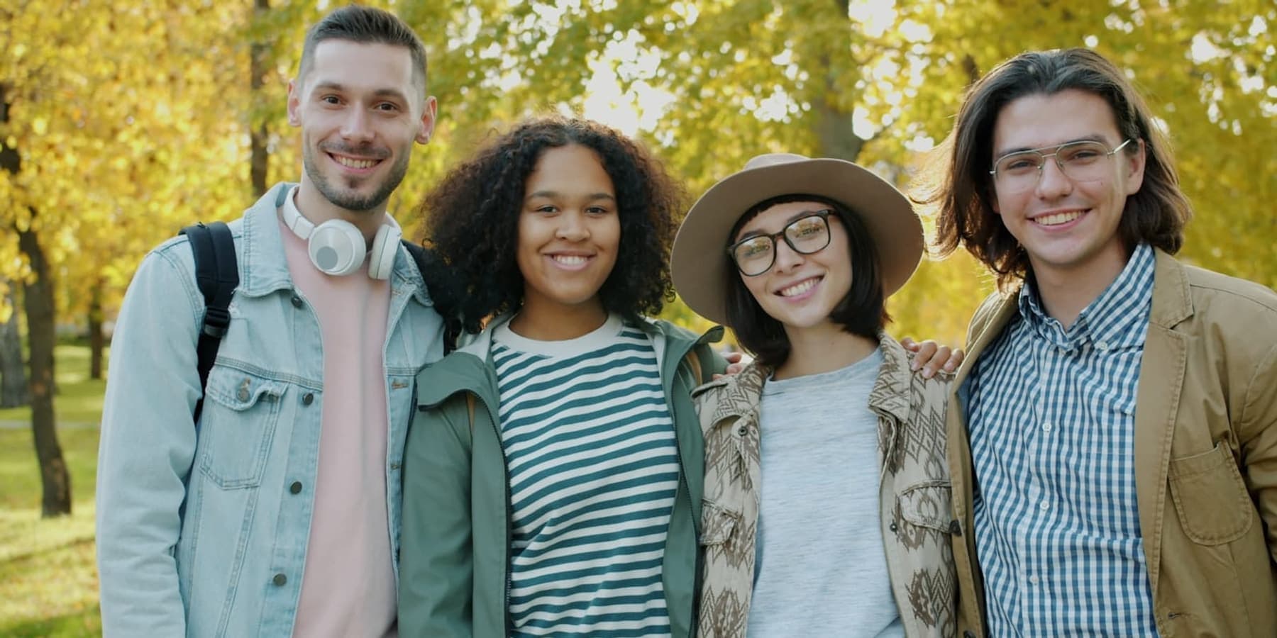 Four friends standing together in a Manchester park on an autumn afternoon