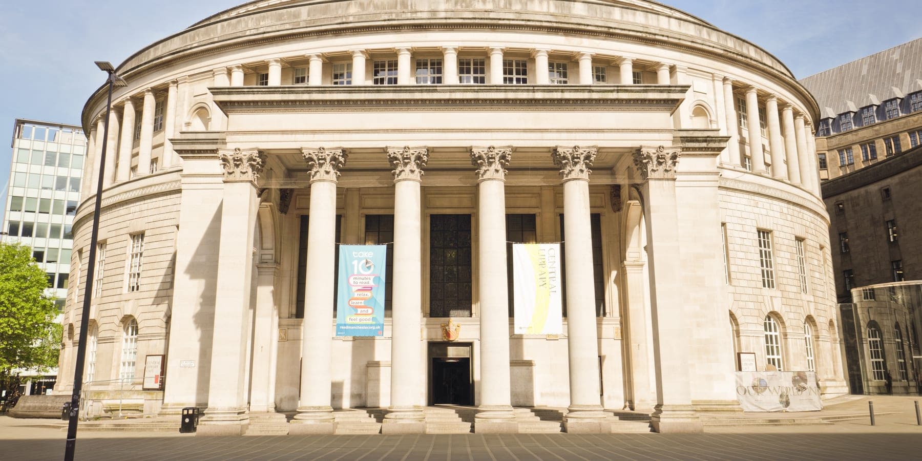 The classical stone portico of Manchester Central Library, its Corinthian columns in afternoon sun